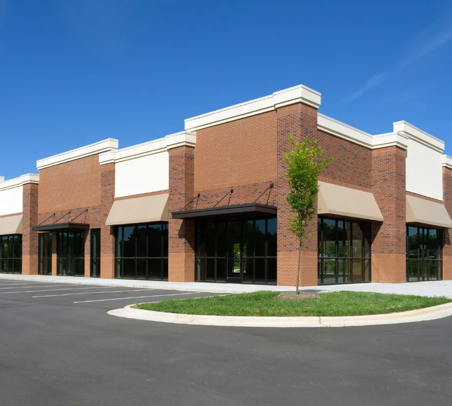 Commercial building construction project in Los Angeles showing newly built retail strip center with brick exterior, storefront glass, and parking area
