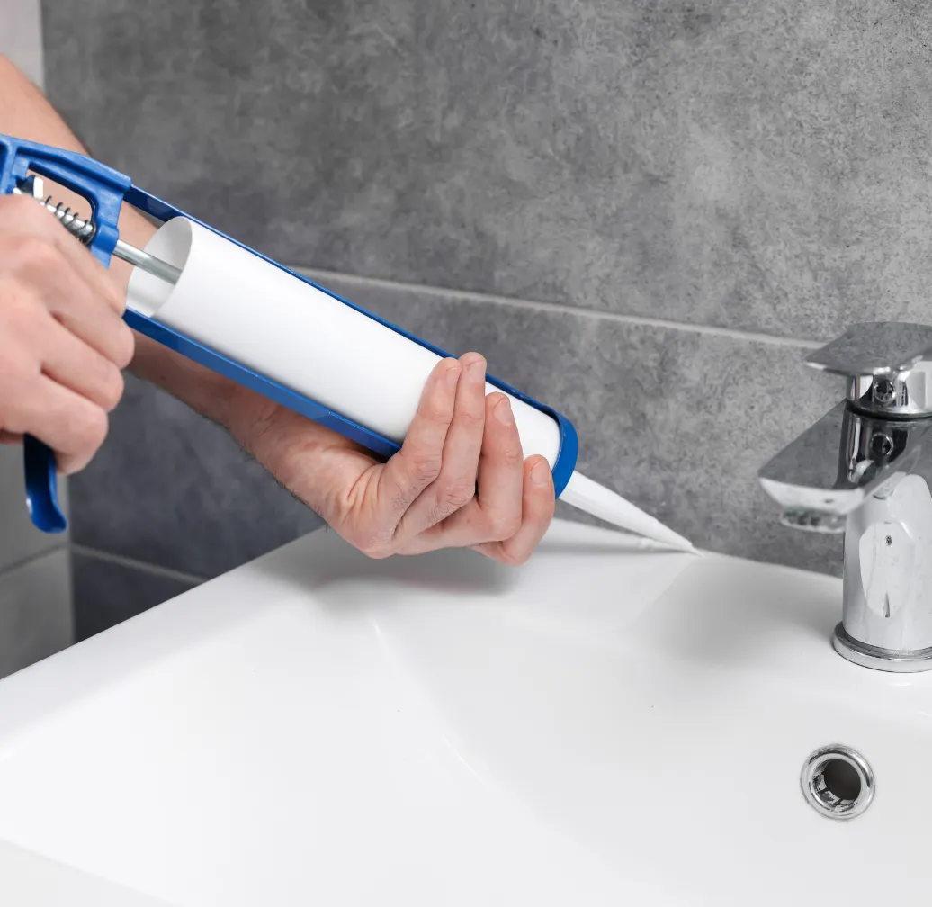 Bathroom remodeling in Los Angeles CA with contractor applying sealant around sink and fixtures for waterproof finishing