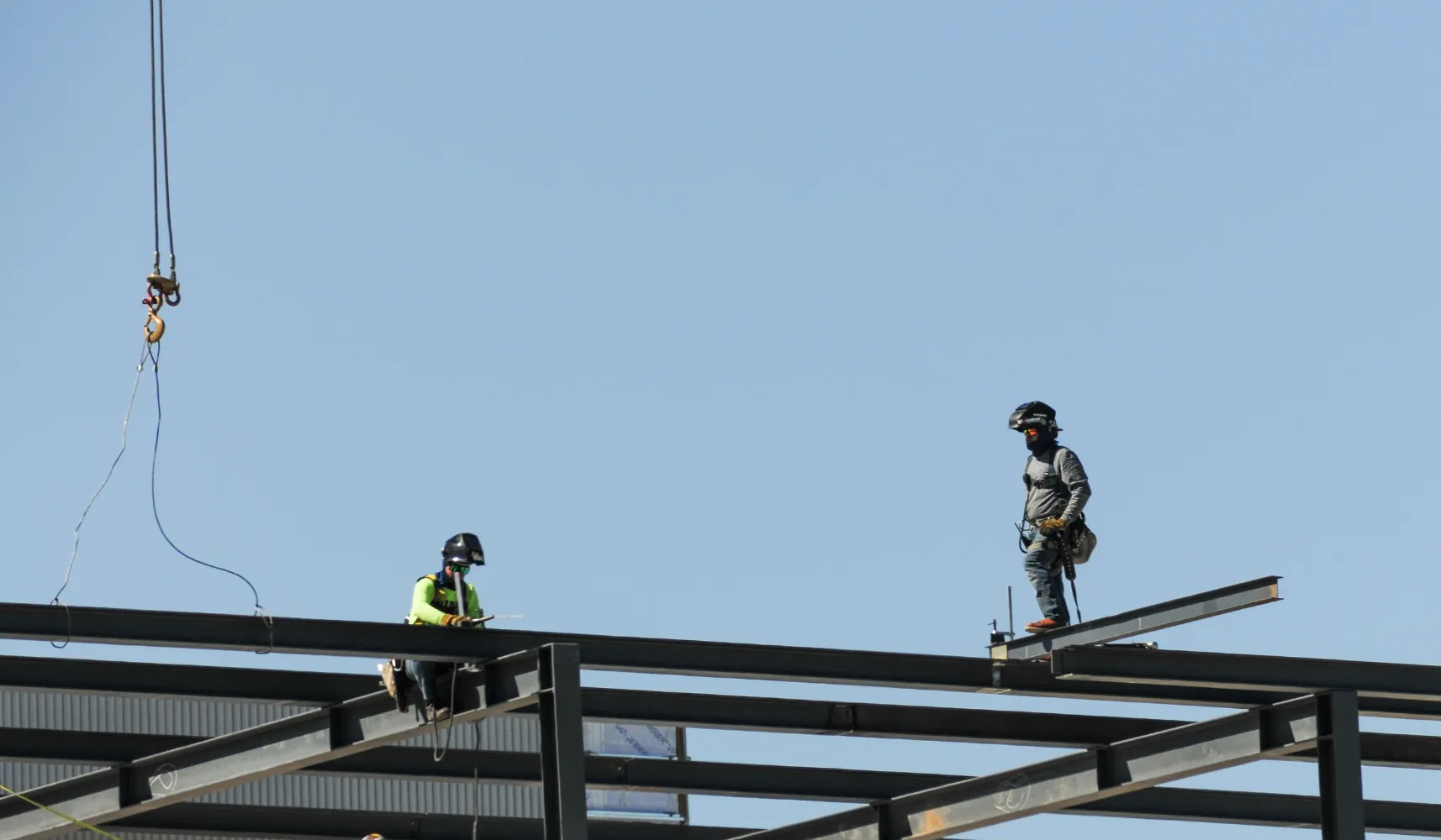 General contractor in Los Angeles overseeing steel structure construction with workers installing metal beams on commercial project