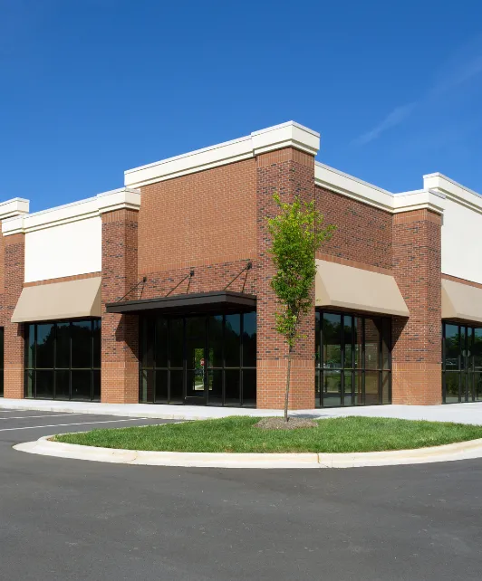 Commercial building construction project in Los Angeles showing completed retail building with brick exterior, storefront windows, and parking area