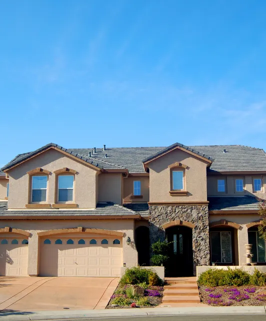 Custom home building project in Los Angeles featuring luxury two-story house with stucco exterior, stone accents, and landscaped front yard